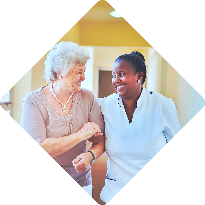 Smiling home caregiver and senior woman walking together